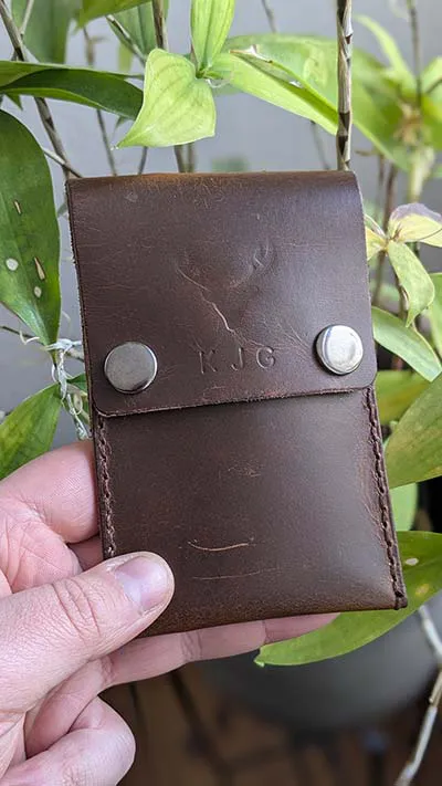 Close-up of hand-stitched leather wallet with rounded edge and contrast stitching